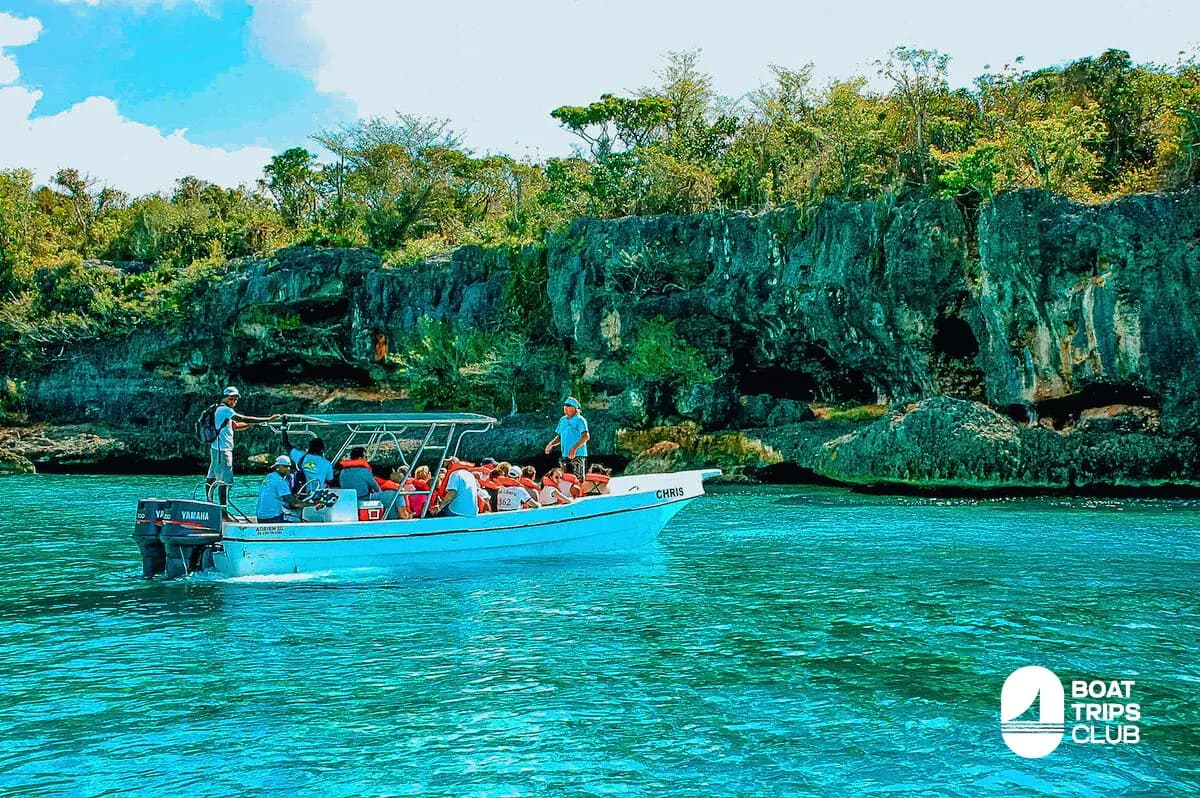 Speedboat carrying guests in life jackets past limestone cliffs off Saona Island