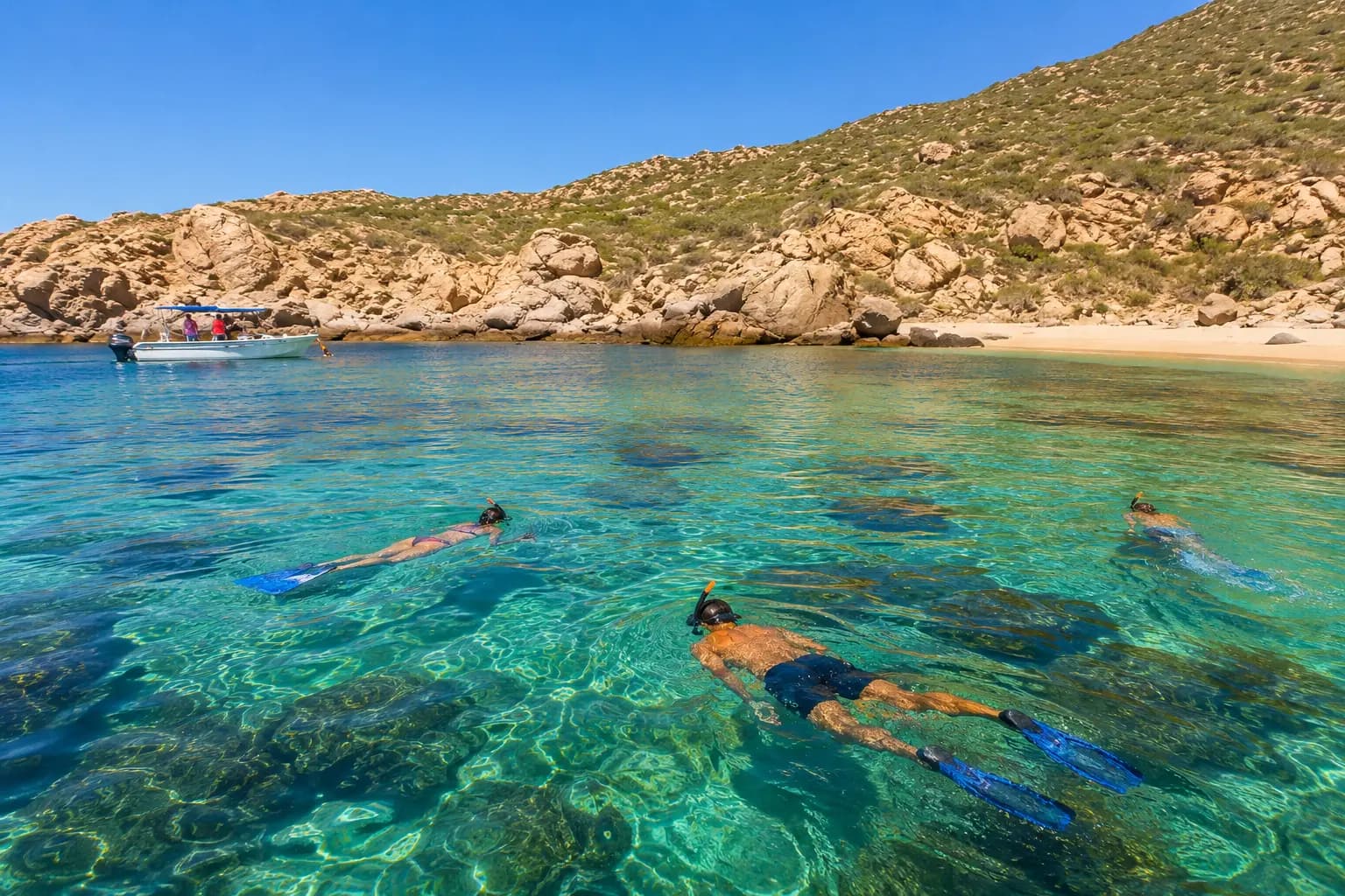 Snorkelers float over the reef in clear turquoise water at Santa María Bay