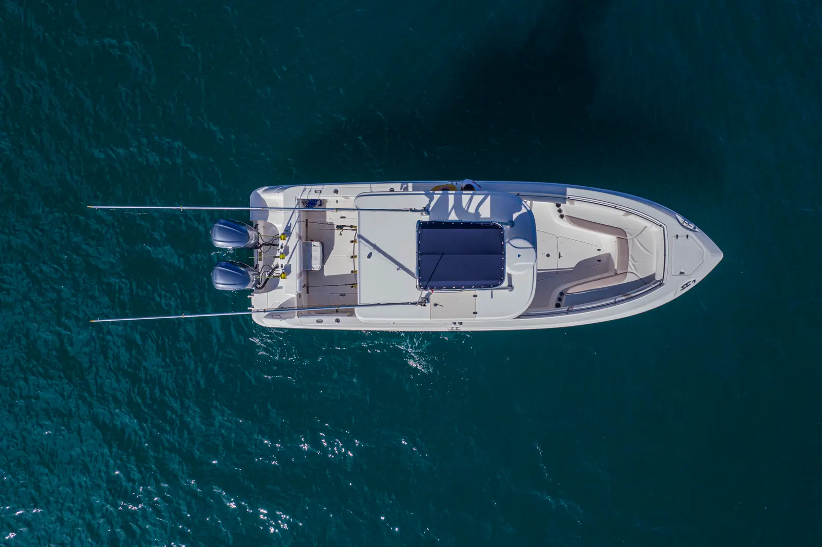 Top-down drone view of the center-console fishing boat drifting on dark teal water