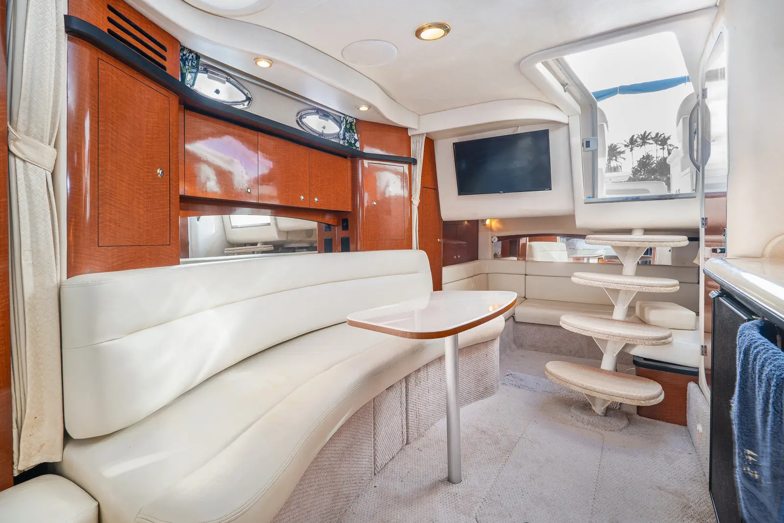 Below-deck salon with a long cream sofa, galley, wall TV and curved steps up to the cockpit