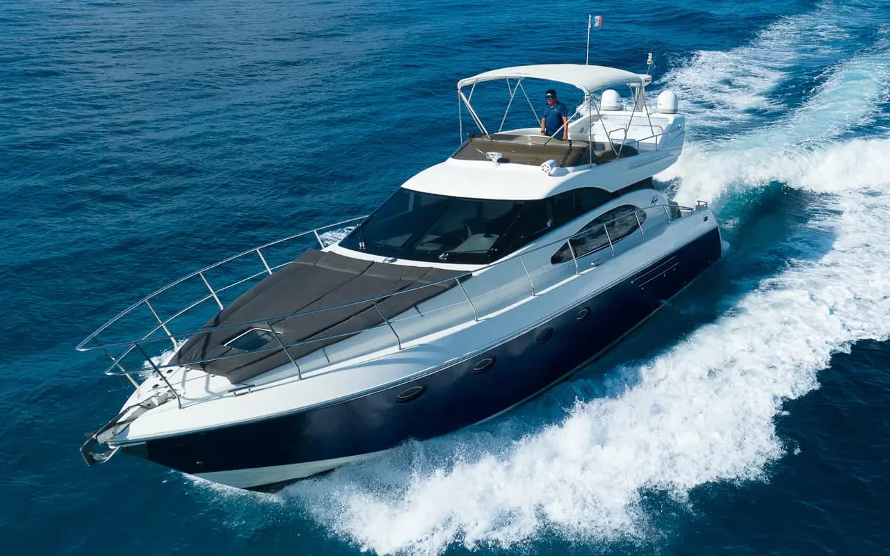 Flybridge motor yacht speeding through deep blue water off the Riviera Maya with a white wake behind