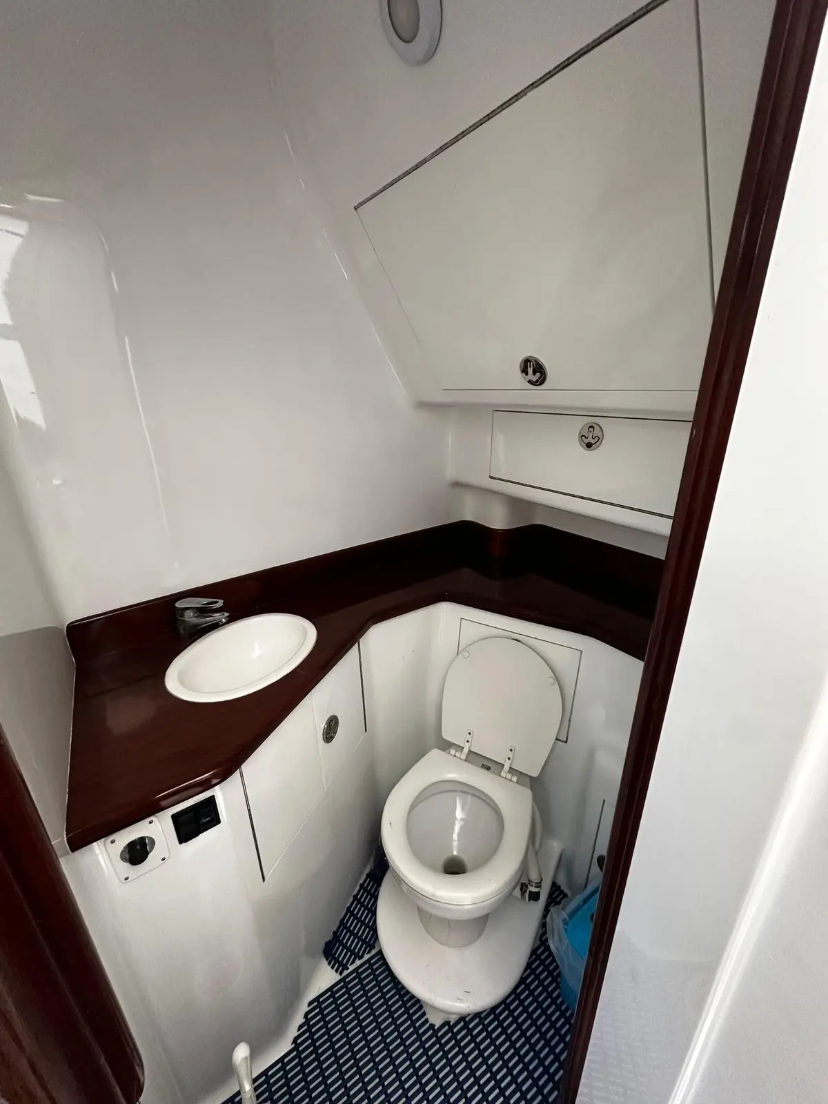 Compact bathroom on the sportfishing boat with a marine toilet, small sink and dark wood counter