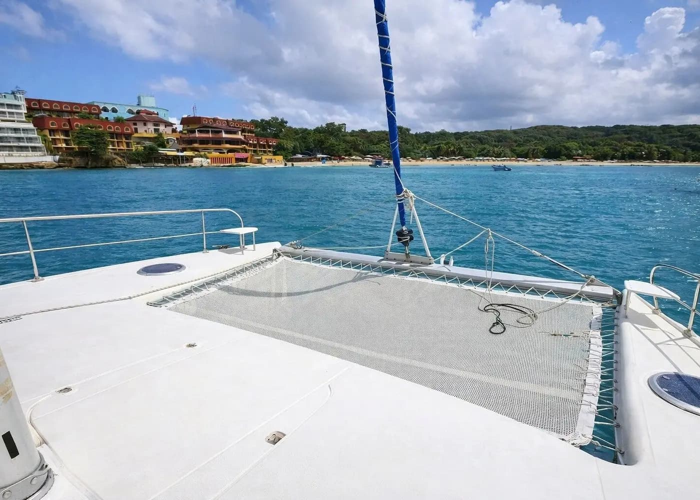 Bow trampoline net of a catamaran facing hotels on the shore of Sosua Bay