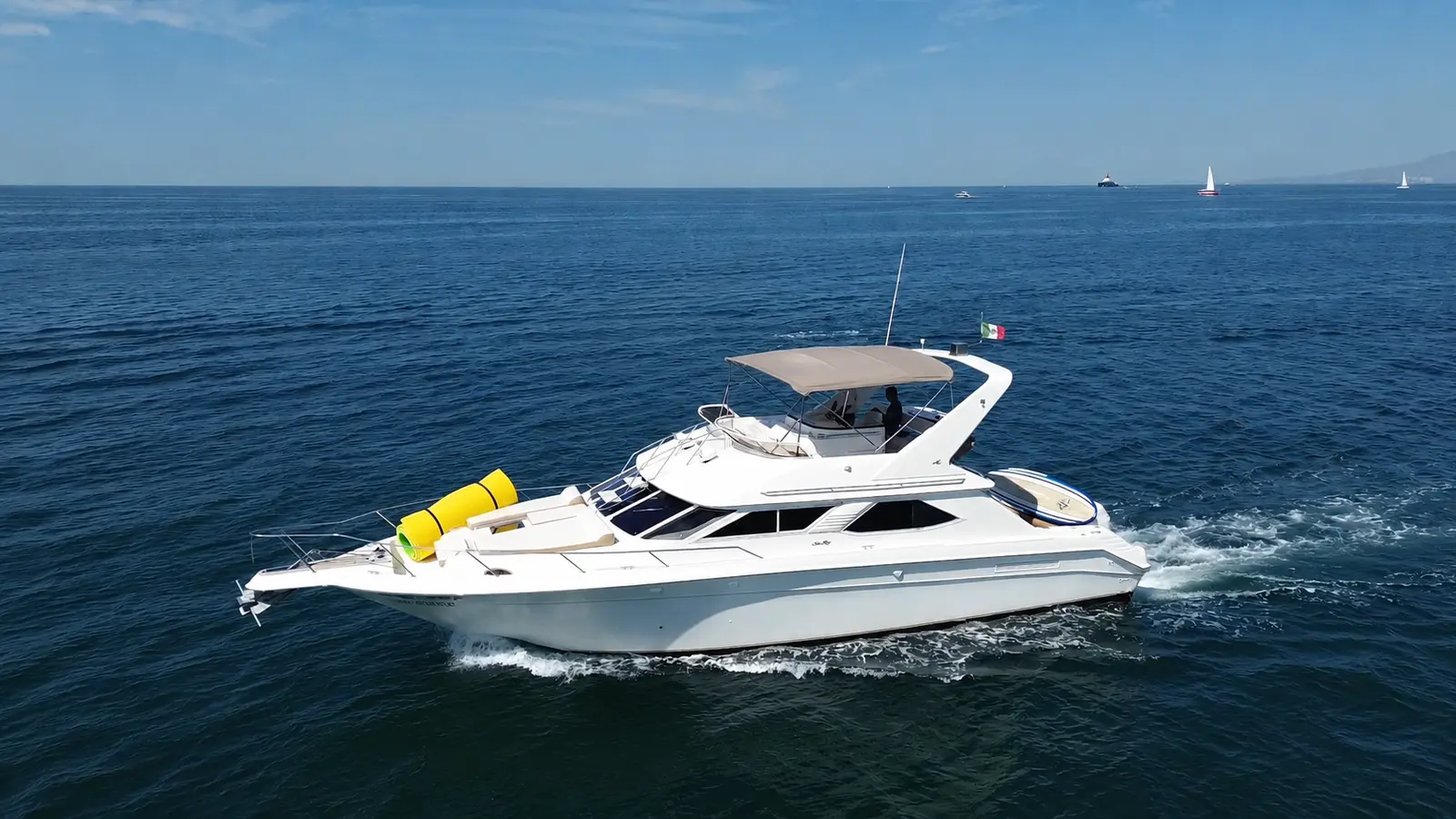 A white flybridge motor yacht cruises across deep blue open water off Puerto Vallarta