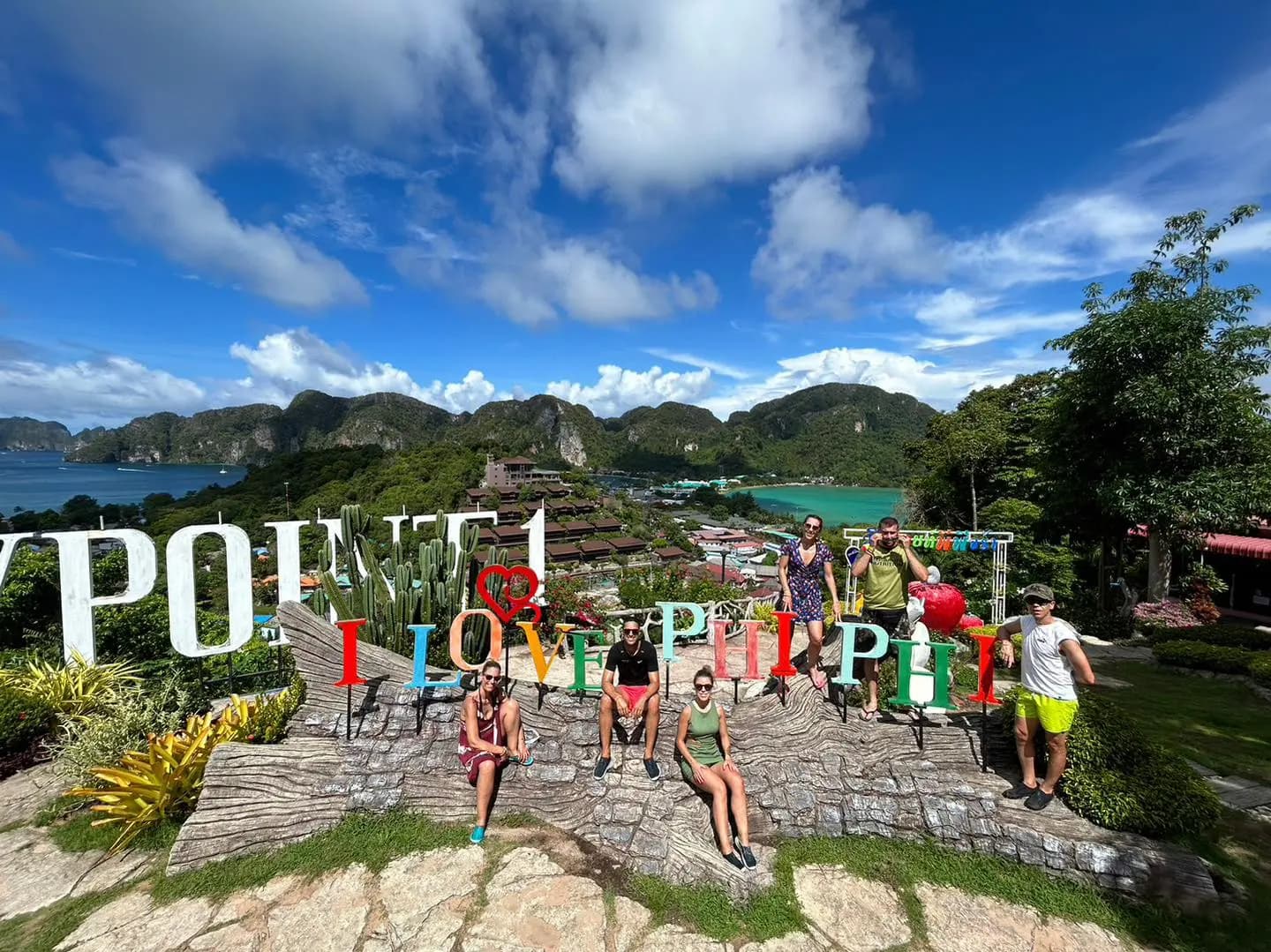 Guests posing by the colorful I Love Phi Phi sign at a hilltop viewpoint above the island's bays