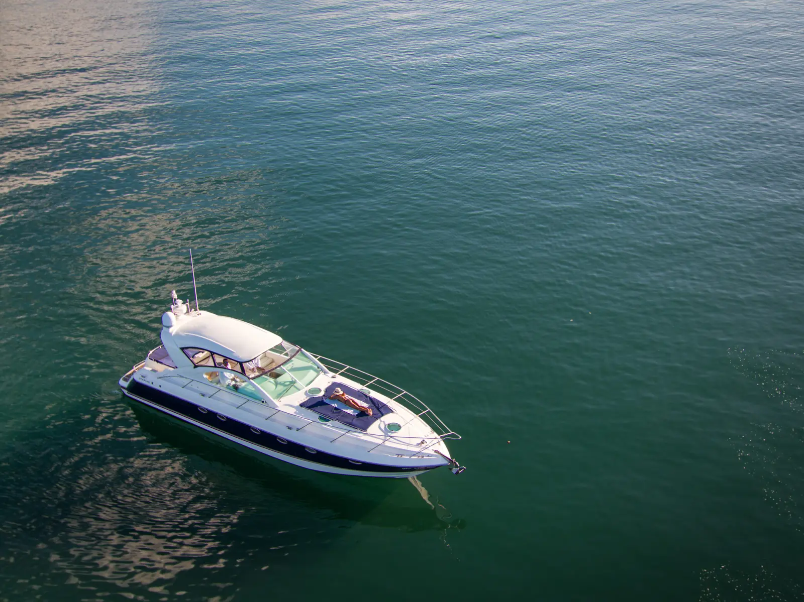 Aerial view of a white sport yacht resting on calm green water in Papagayo