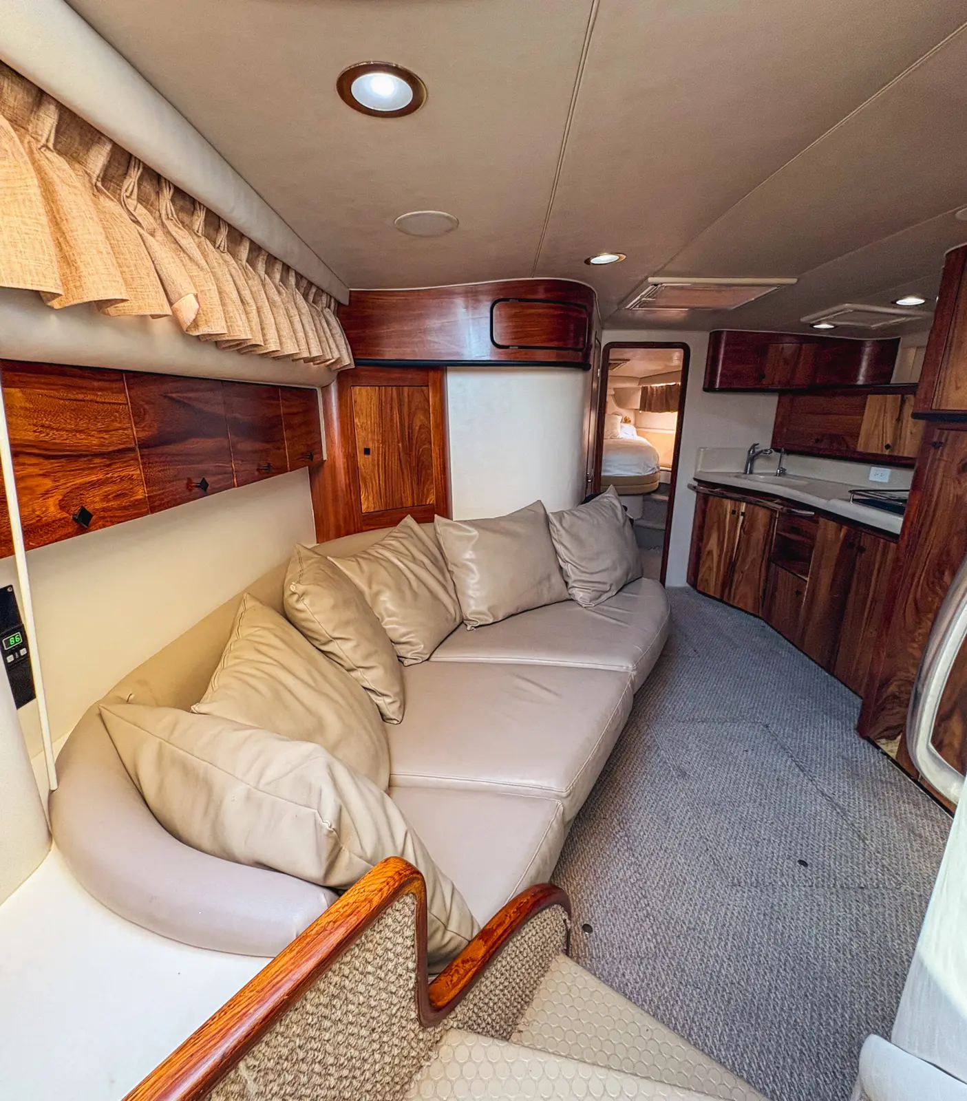 Yacht cabin with a cream leather settee, cushions and glossy wood cabinetry