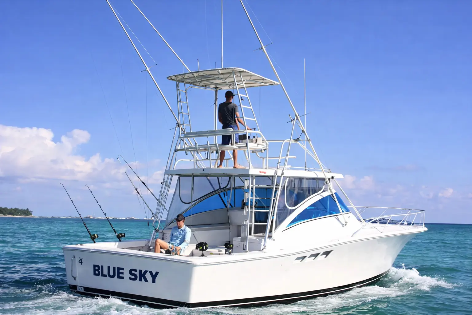 Sportfishing boat seen from the stern with outriggers up and a crew member on the tuna tower