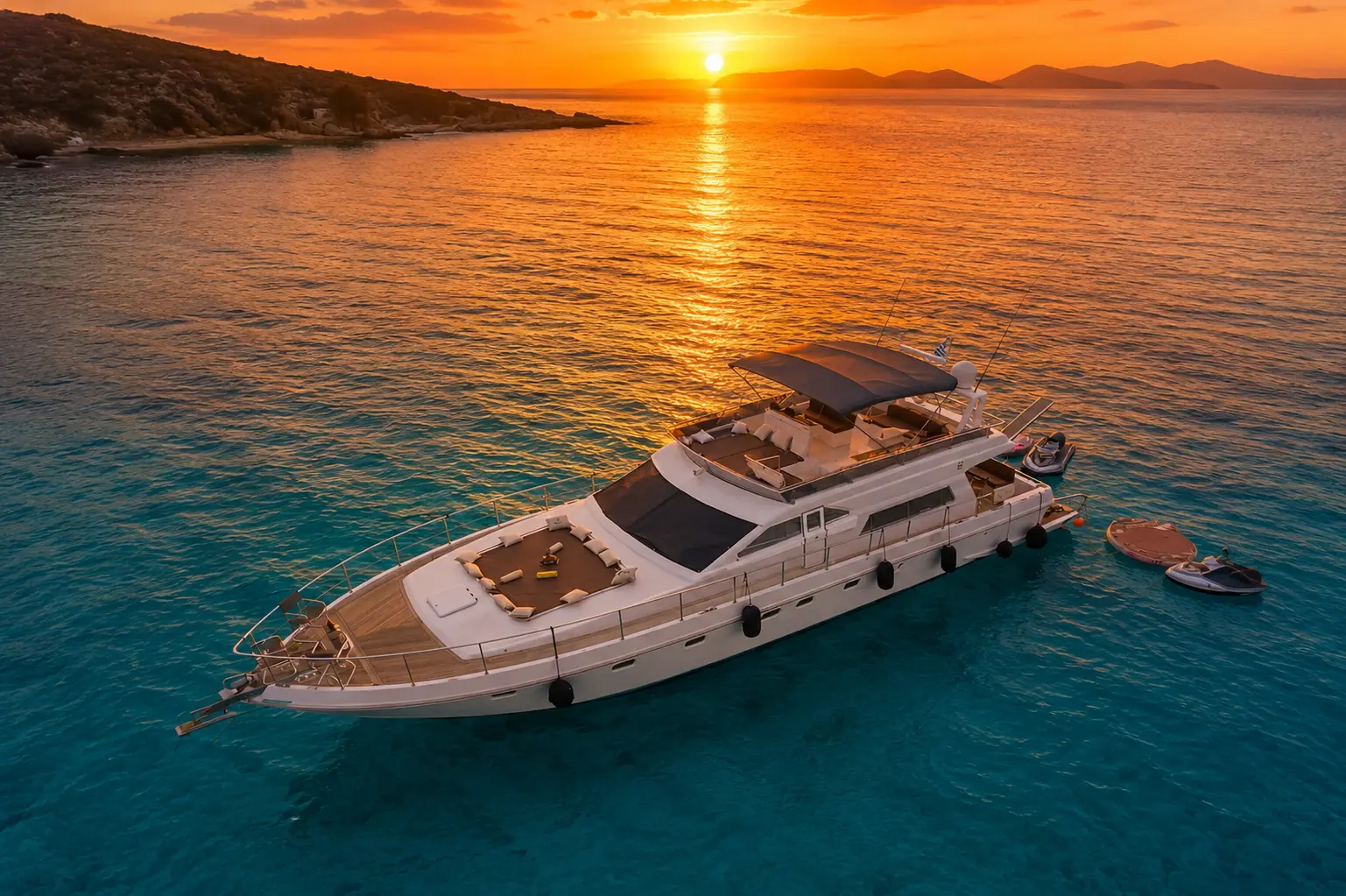 Aerial view of a large motor yacht anchored off Mykonos as the sun sets over the hills