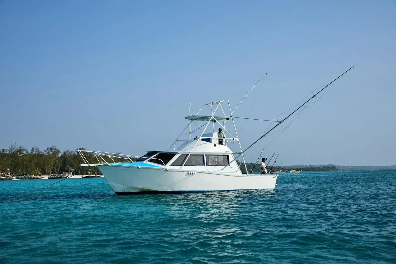 Sportfishing boat with a tuna tower and outriggers anchored in turquoise water off Zanzibar