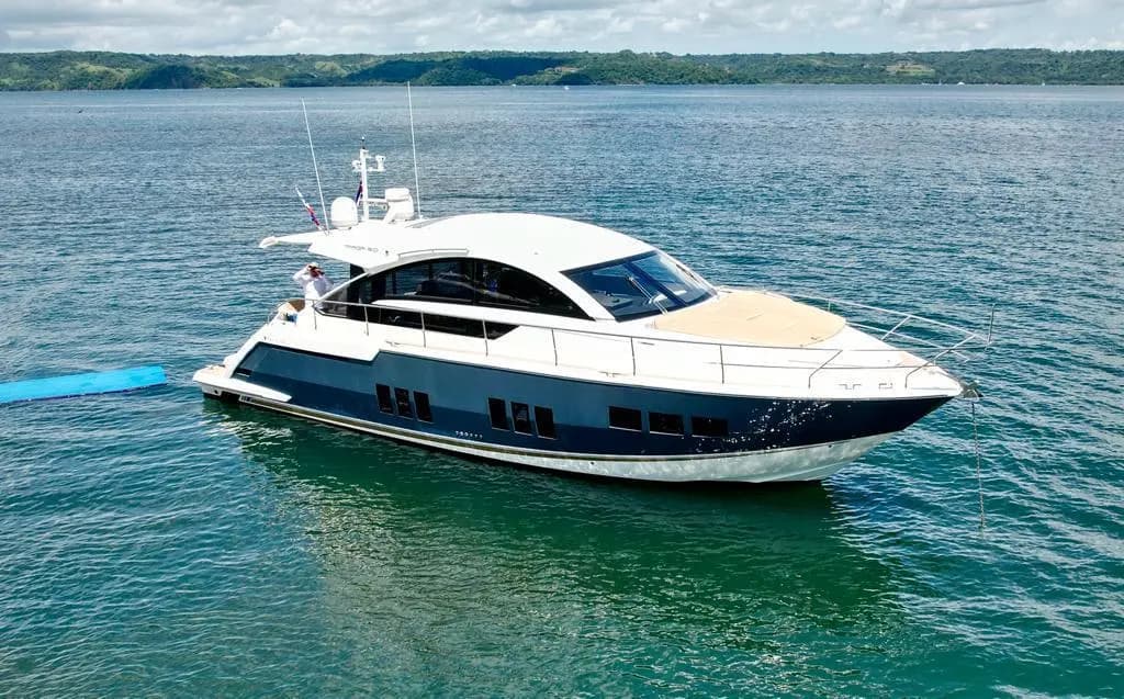 Navy-hulled motor yacht anchored in calm green water along the Papagayo coastline