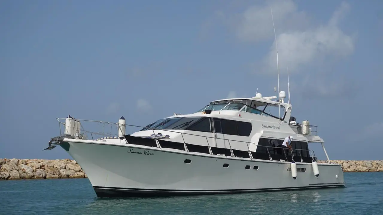 Flybridge motor yacht on calm water beside a rock breakwater in Punta Cana