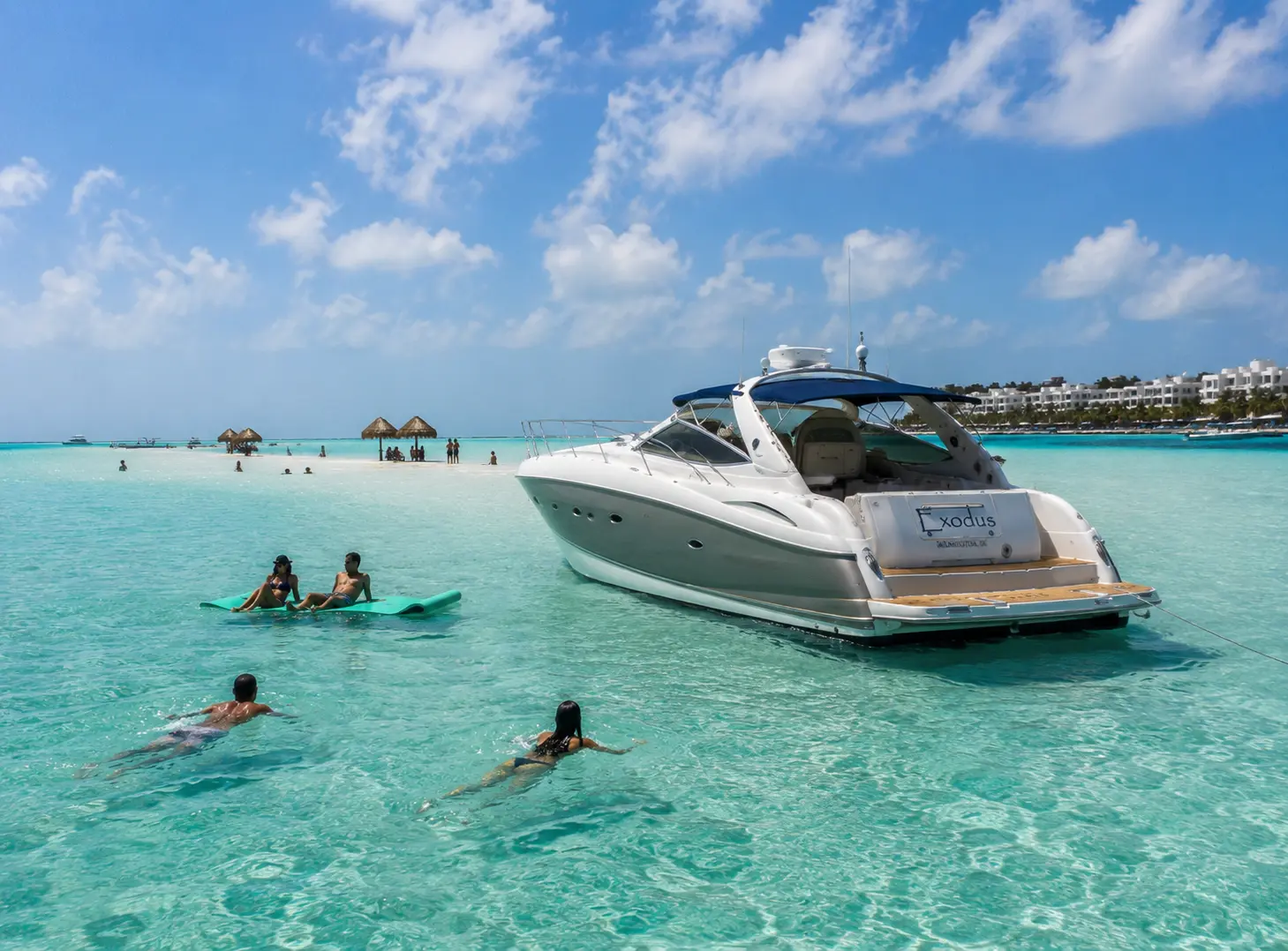 Motor yacht anchored in turquoise shallows as guests swim and float on a mat near Isla Mujeres