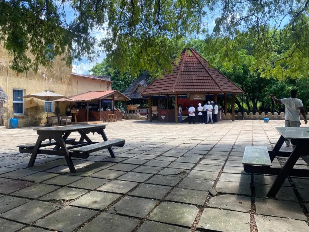 Stone-paved courtyard with picnic benches and a red-roofed gazebo on Prison Island