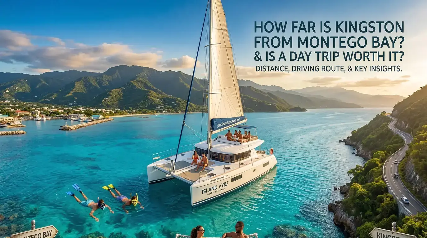 Catamaran with guests in a turquoise Jamaican bay, snorkelers nearby and a coastal road below green mountains
