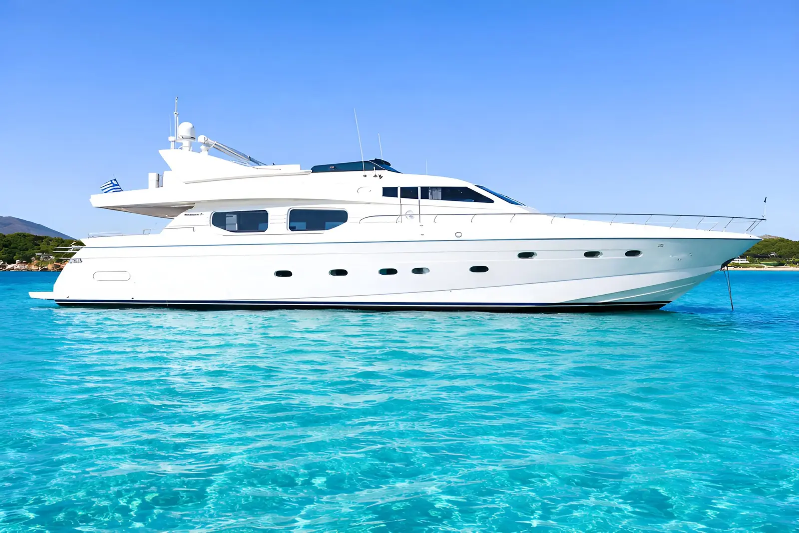 White motor yacht anchored in clear turquoise shallows off a green shoreline near Mykonos