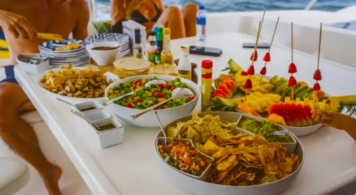 Spread of tortilla chips, pico de gallo, salad and fruit skewers on the deck table