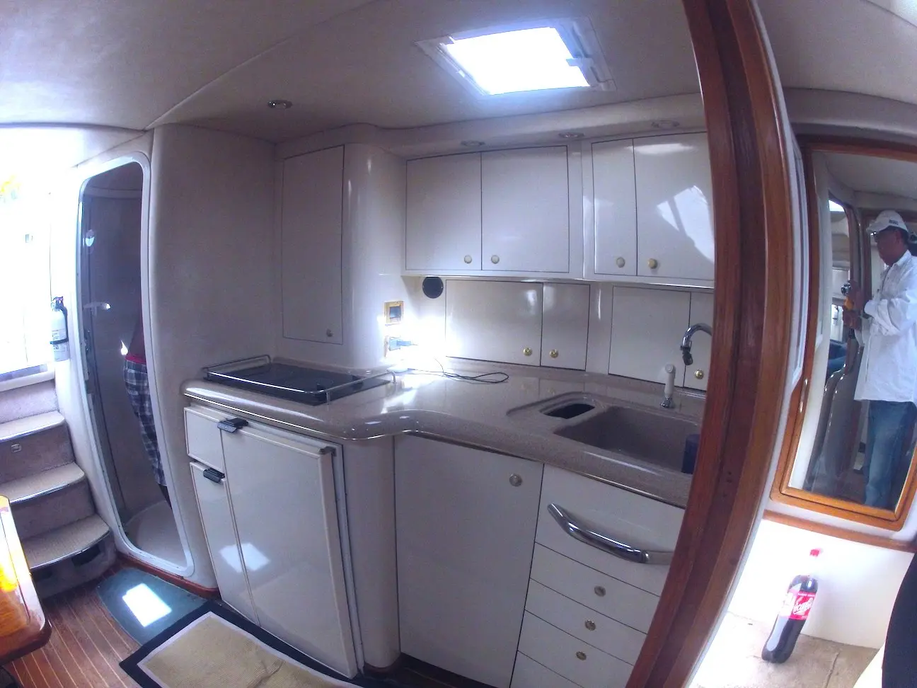 Compact yacht galley with white cabinets, a sink and a cooktop