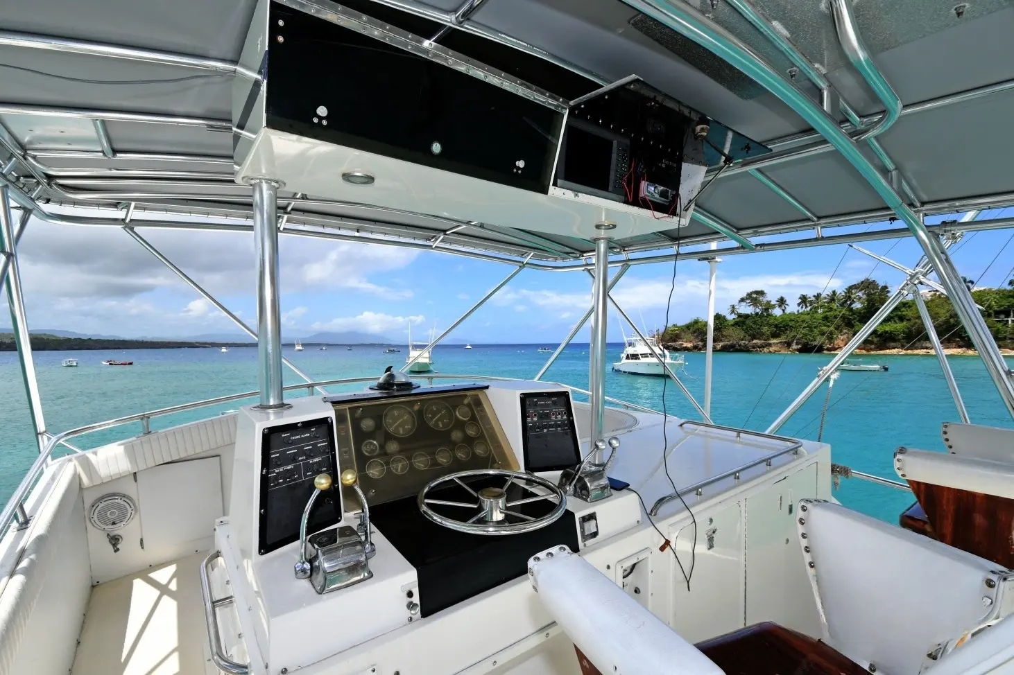Flybridge helm of a sportfishing boat with wheel and electronics overlooking turquoise water off Puerto Plata