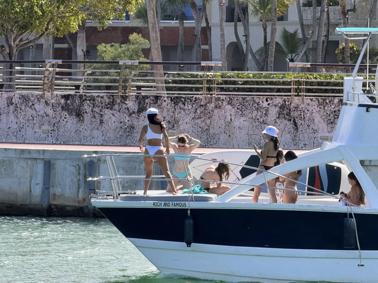 Women in swimsuits and sun hats gather on the deck of the catamaran docked at the Cap Cana marina