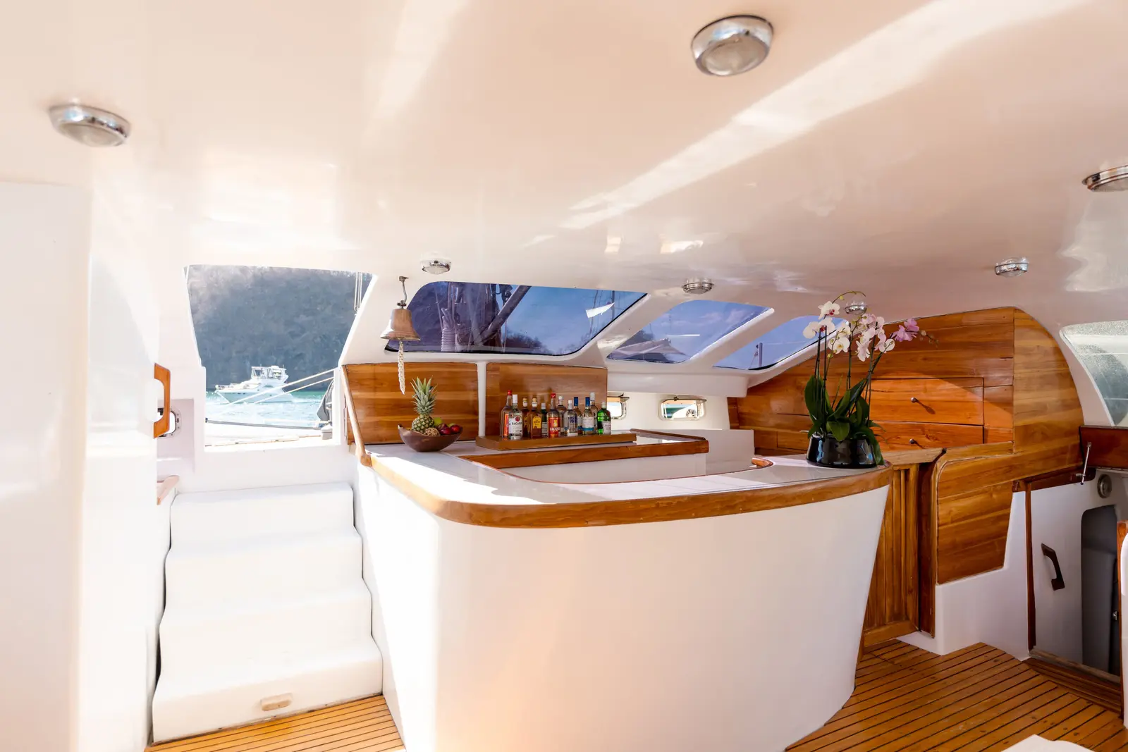 Catamaran salon with a curved wood-topped bar, liquor shelf and orchids