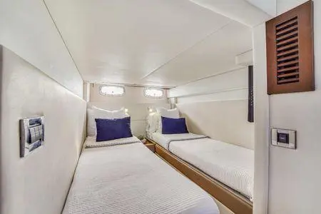 Yacht guest cabin with twin single beds, white linens and navy pillows