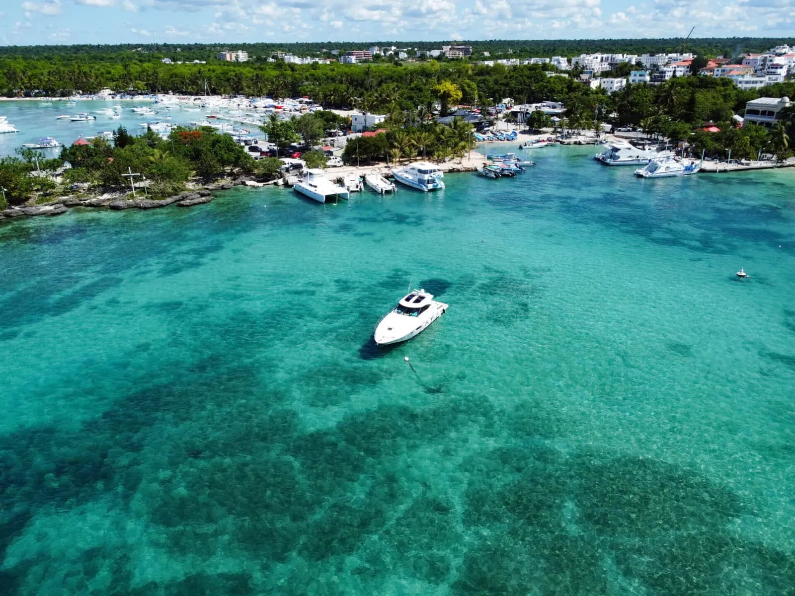 Aerial view of a motor yacht in turquoise water off Bayahibe, boats moored along the coast