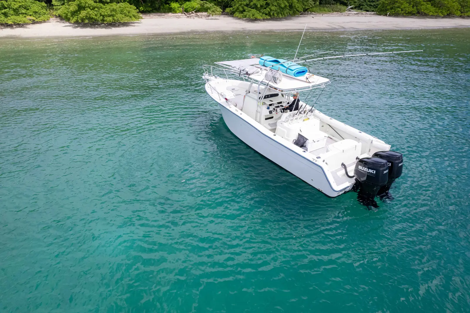 Aerial view of a center-console fishing boat with twin outboards anchored in clear turquoise water in Papagayo