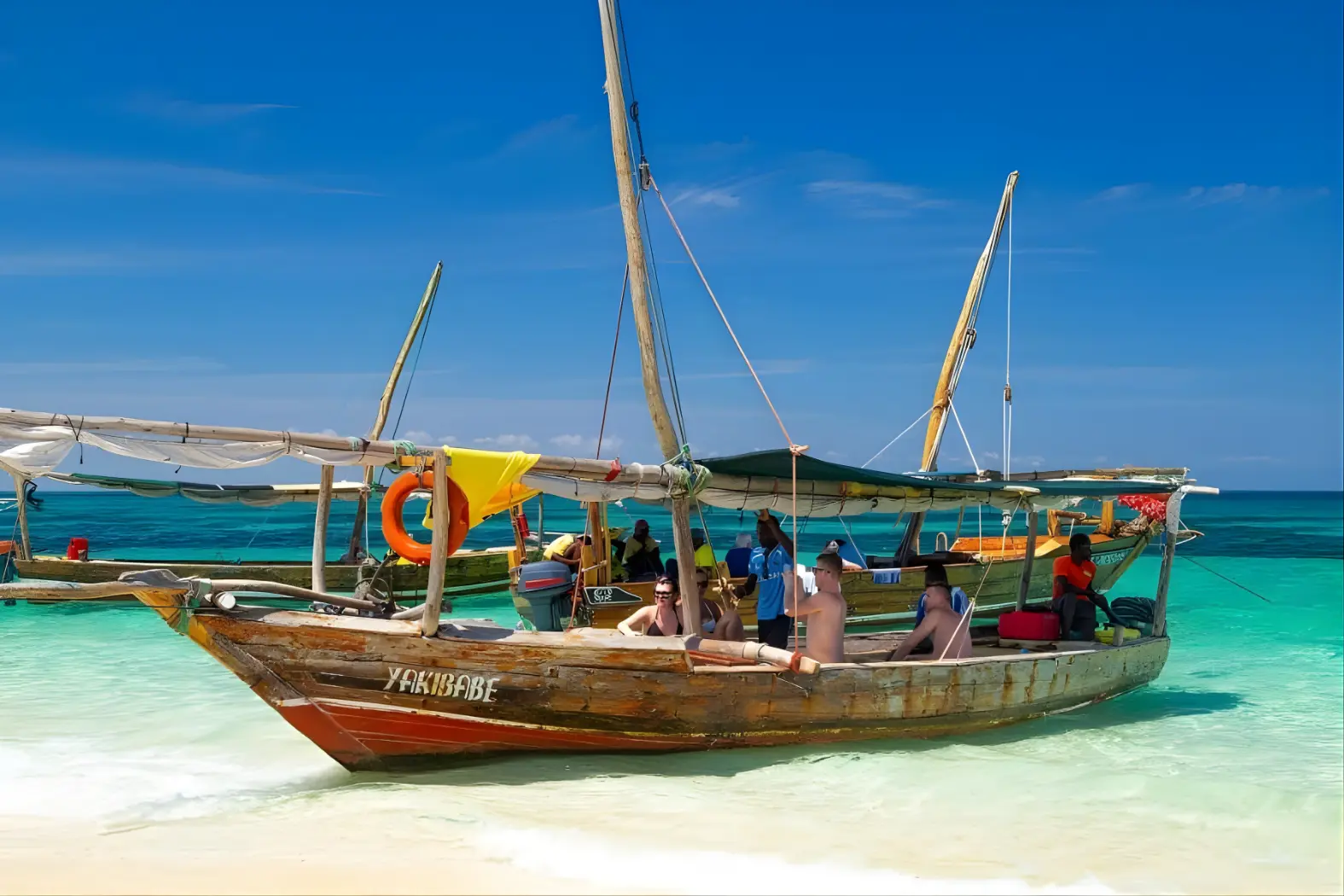 Traditional wooden boat with guests on a white-sand beach near Stone Town, Zanzibar