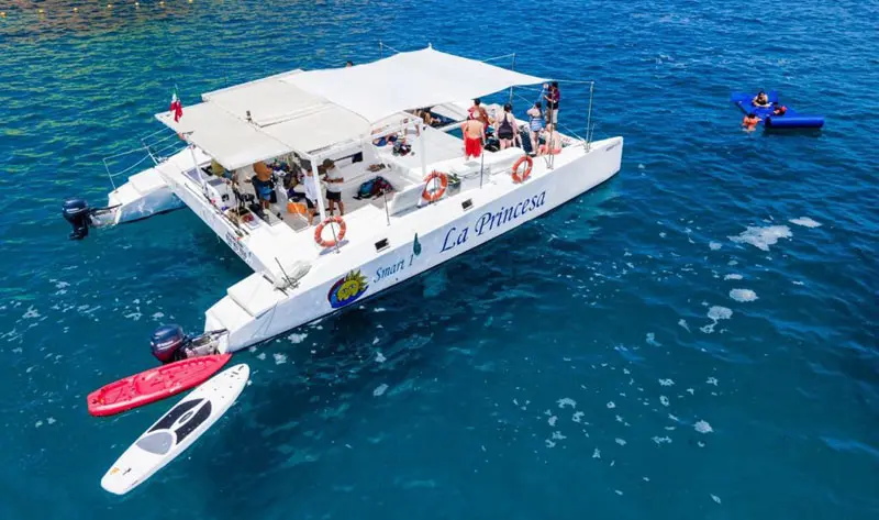 Aerial view of the catamaran anchored in deep blue water off Cabo San Lucas with paddleboards at the stern