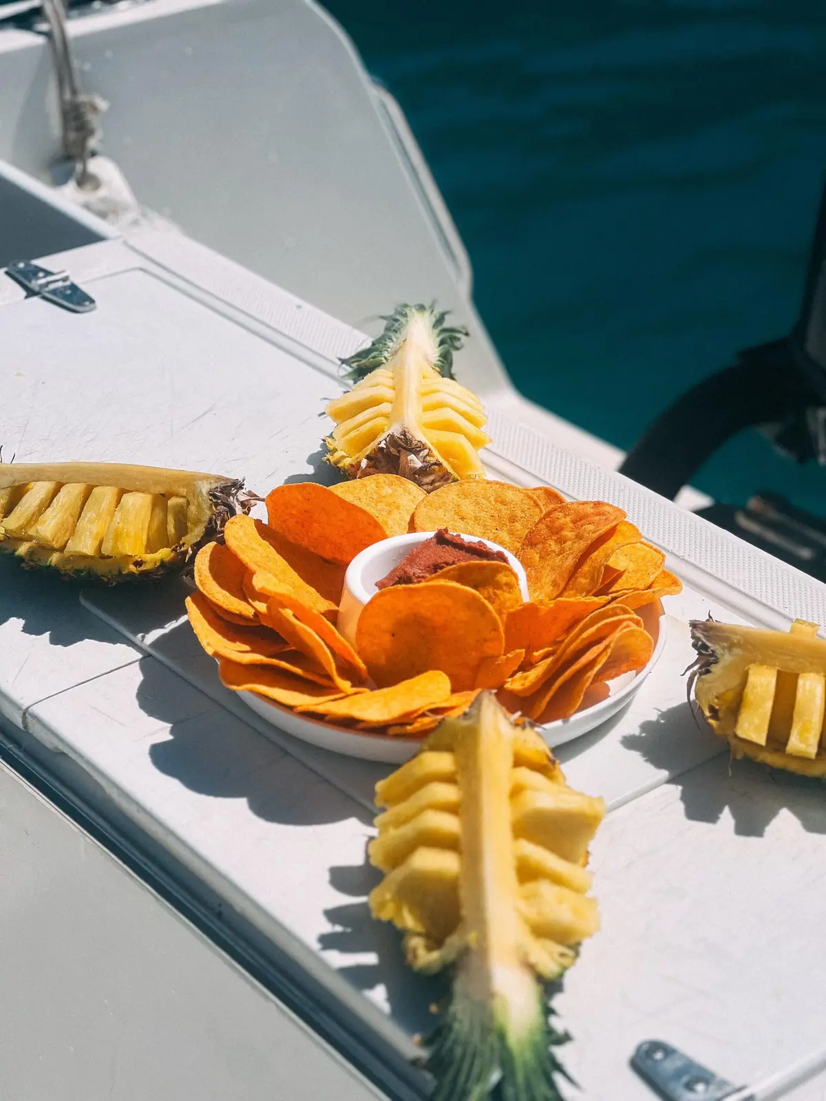 Pineapple wedges and a plate of tortilla chips with dip set out on board the fishing boat