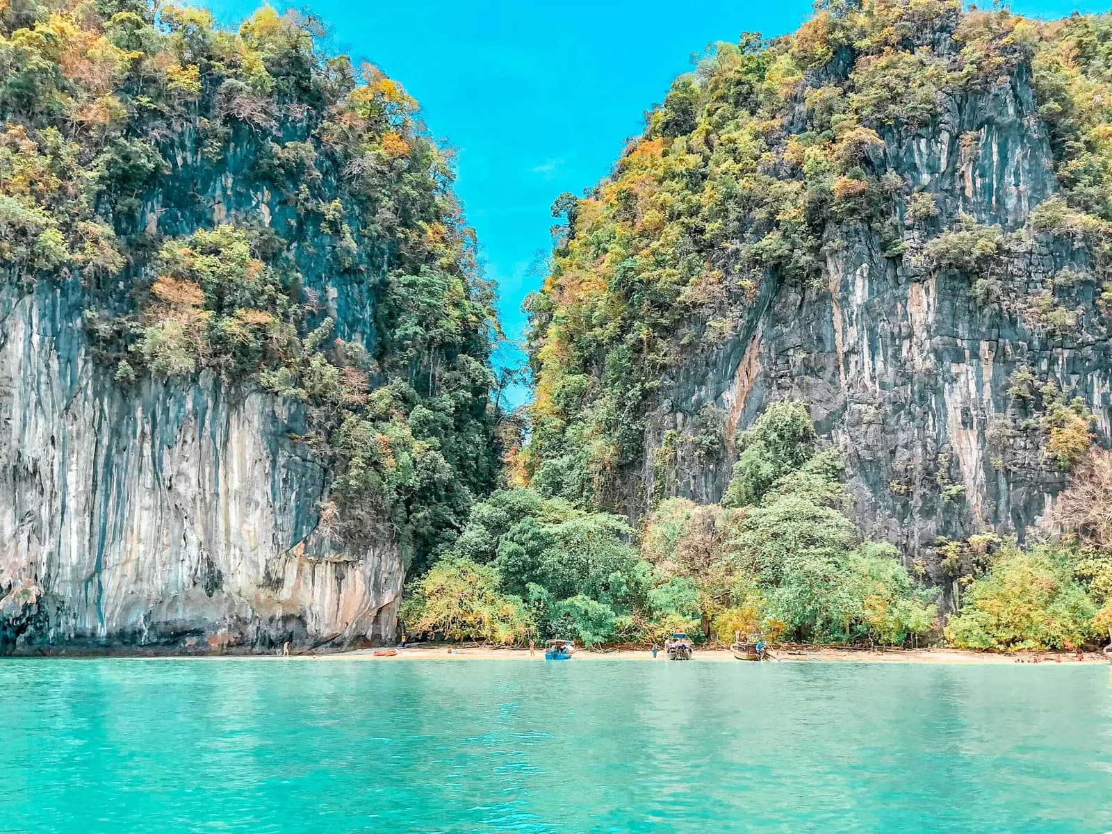 Two jungle-topped limestone towers flanking a narrow beach above turquoise water on Hong Island