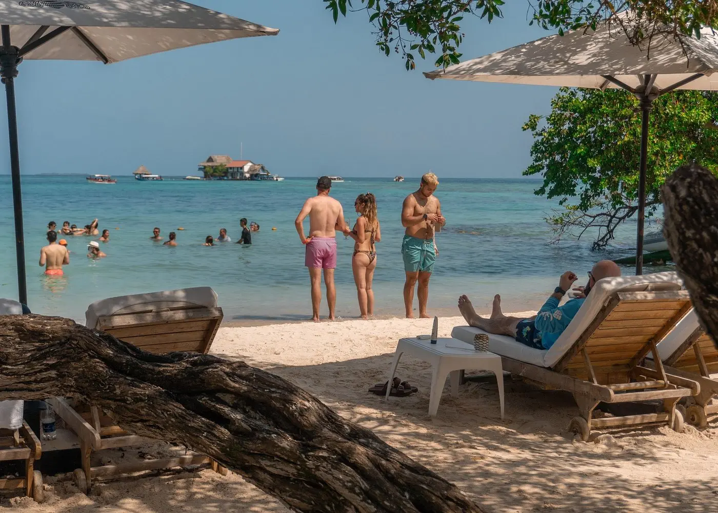 Guests wading in shallow turquoise water and lounging on sunbeds at a Rosario Islands beach club