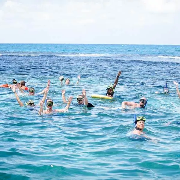 A group of snorkelers waving from open water near the reef off Ocho Rios