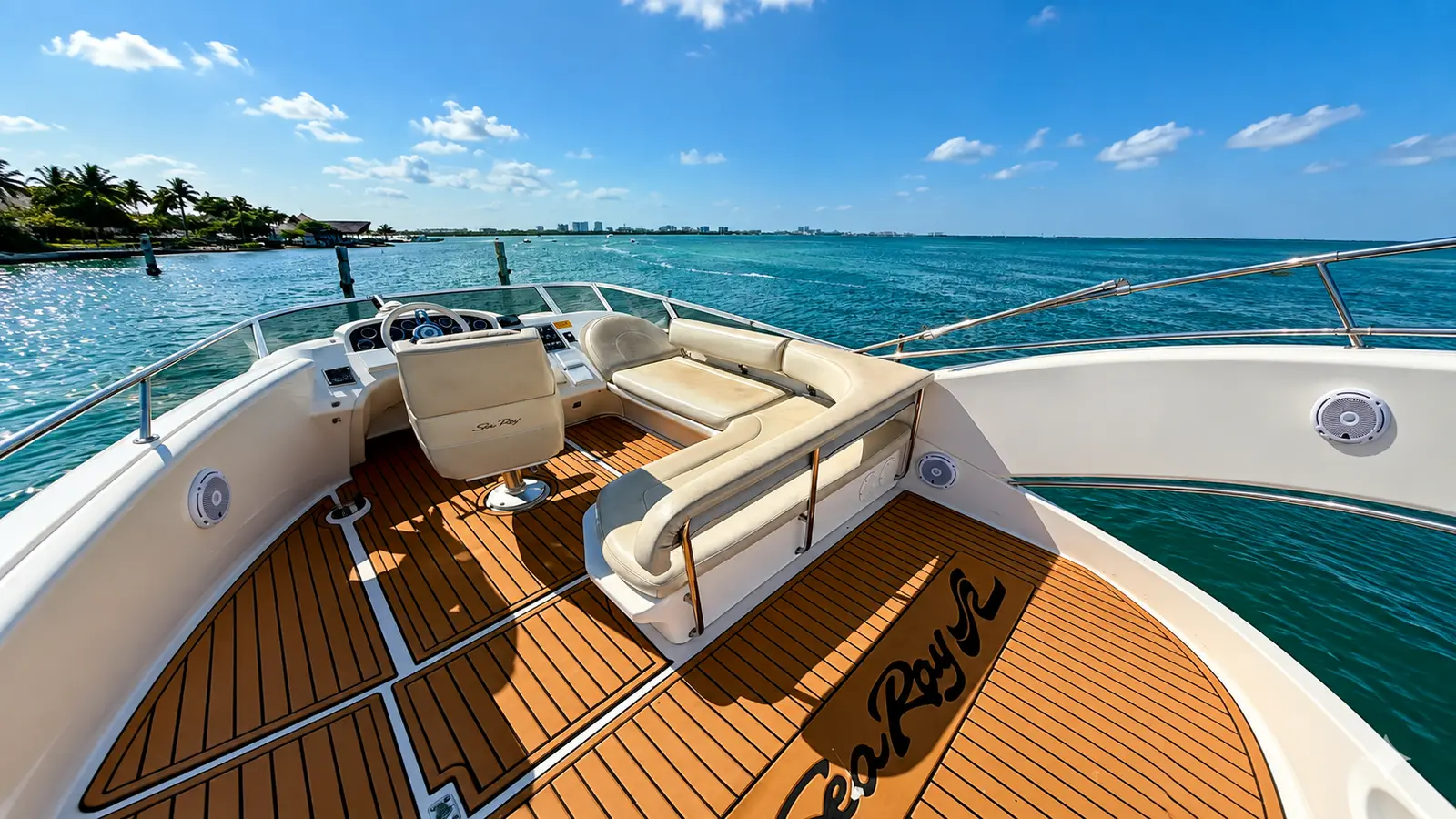Upper helm deck of a flybridge yacht with white seats and teak floor overlooking the Cancún coast
