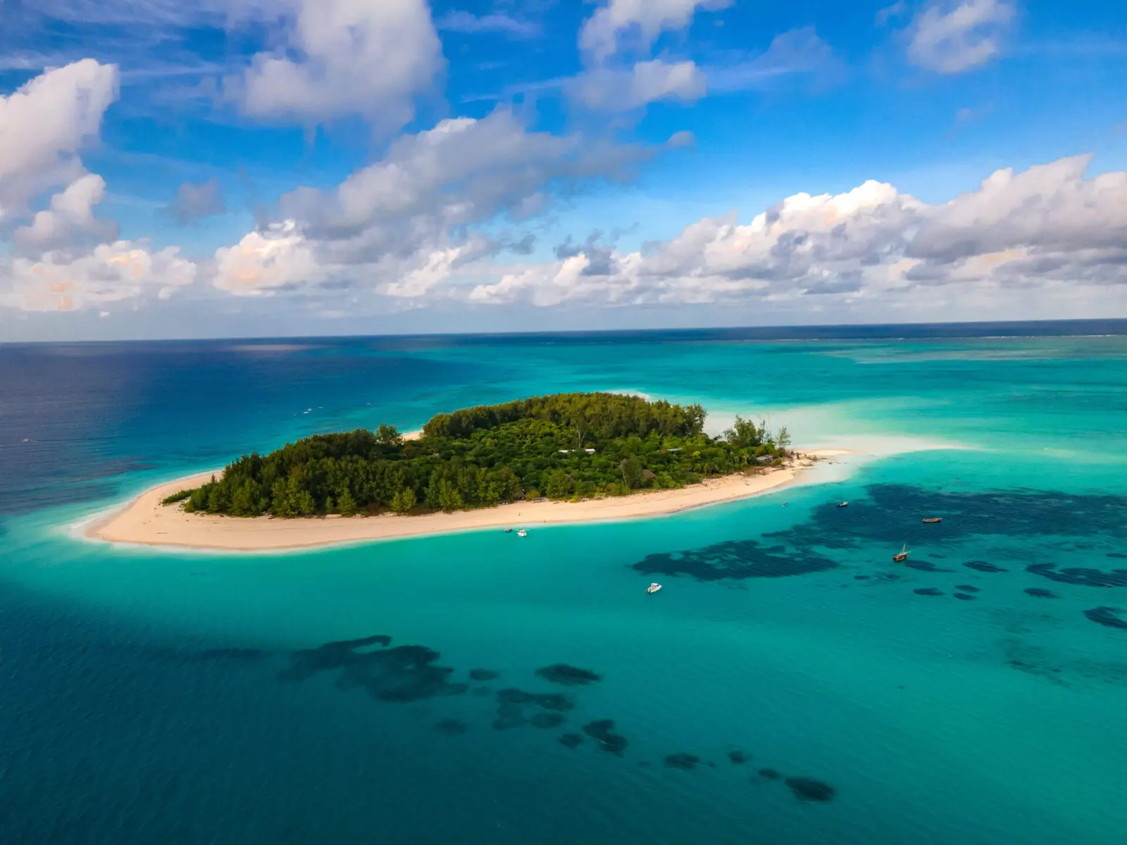 Aerial view of Mnemba Island, a small wooded isle ringed by white sand and turquoise reef
