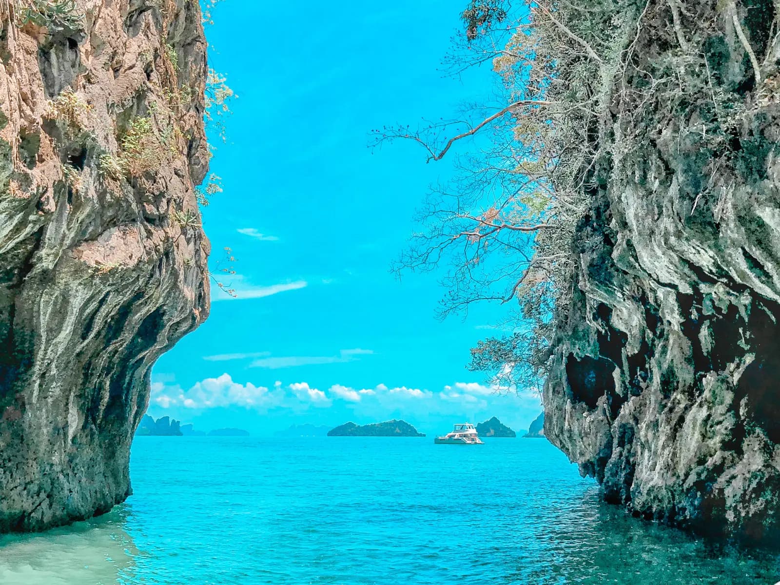 Turquoise channel between two sheer limestone walls opening onto distant islands off Krabi