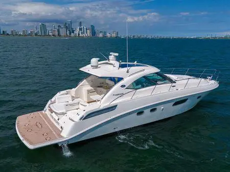 Yacht with a teak swim platform on open water with a city skyline behind
