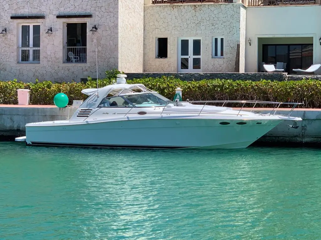 Motor yacht moored along a turquoise canal in front of stone-clad villas in Cap Cana