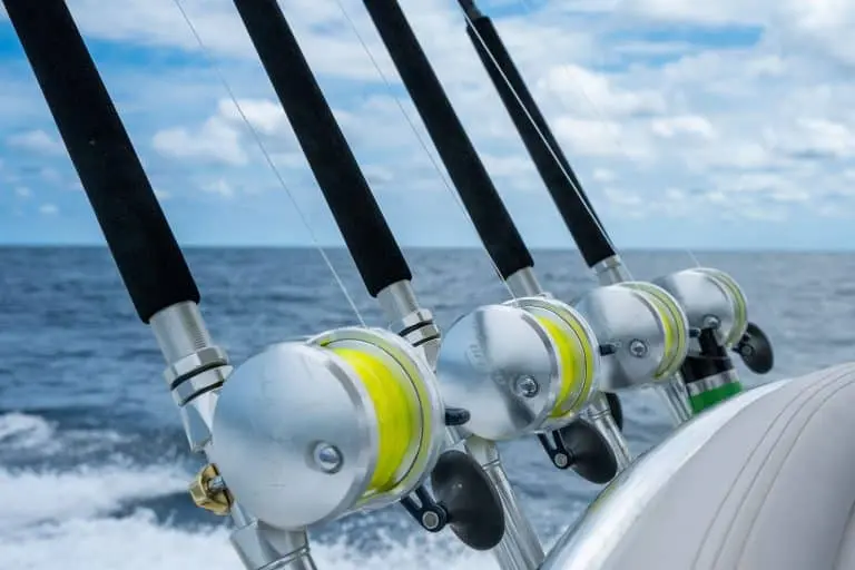 Row of trolling rods and reels spooled with yellow line in the holders of a sportfishing boat