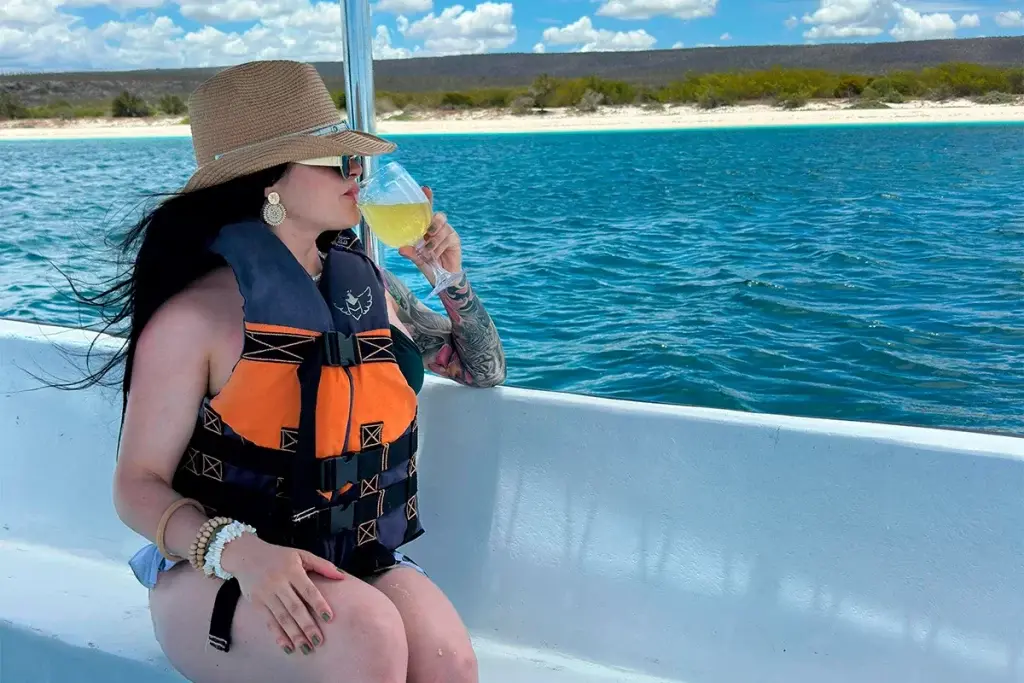 Woman in a straw hat and life vest sipping white wine aboard a catamaran off Cabo Rojo