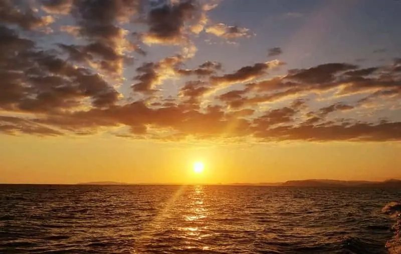 Sun dropping to the horizon under streaked golden clouds over the sea off Costa Rica