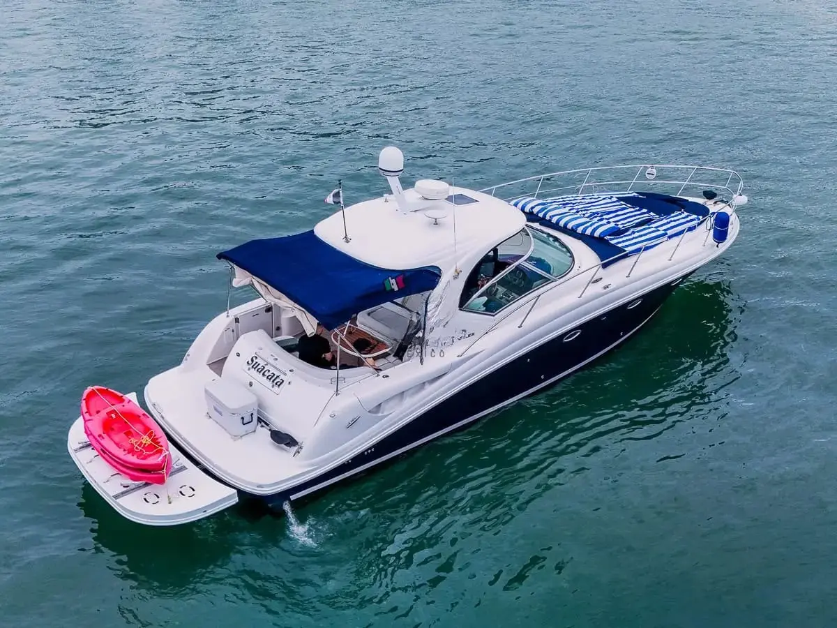 Aerial view of a navy and white motor yacht anchored off Puerto Vallarta, a red kayak on its swim platform