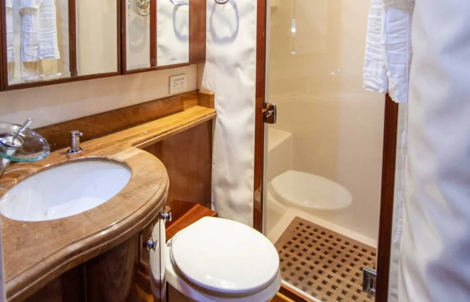 Onboard bathroom with a marble vanity sink, toilet and shower with a teak floor grate