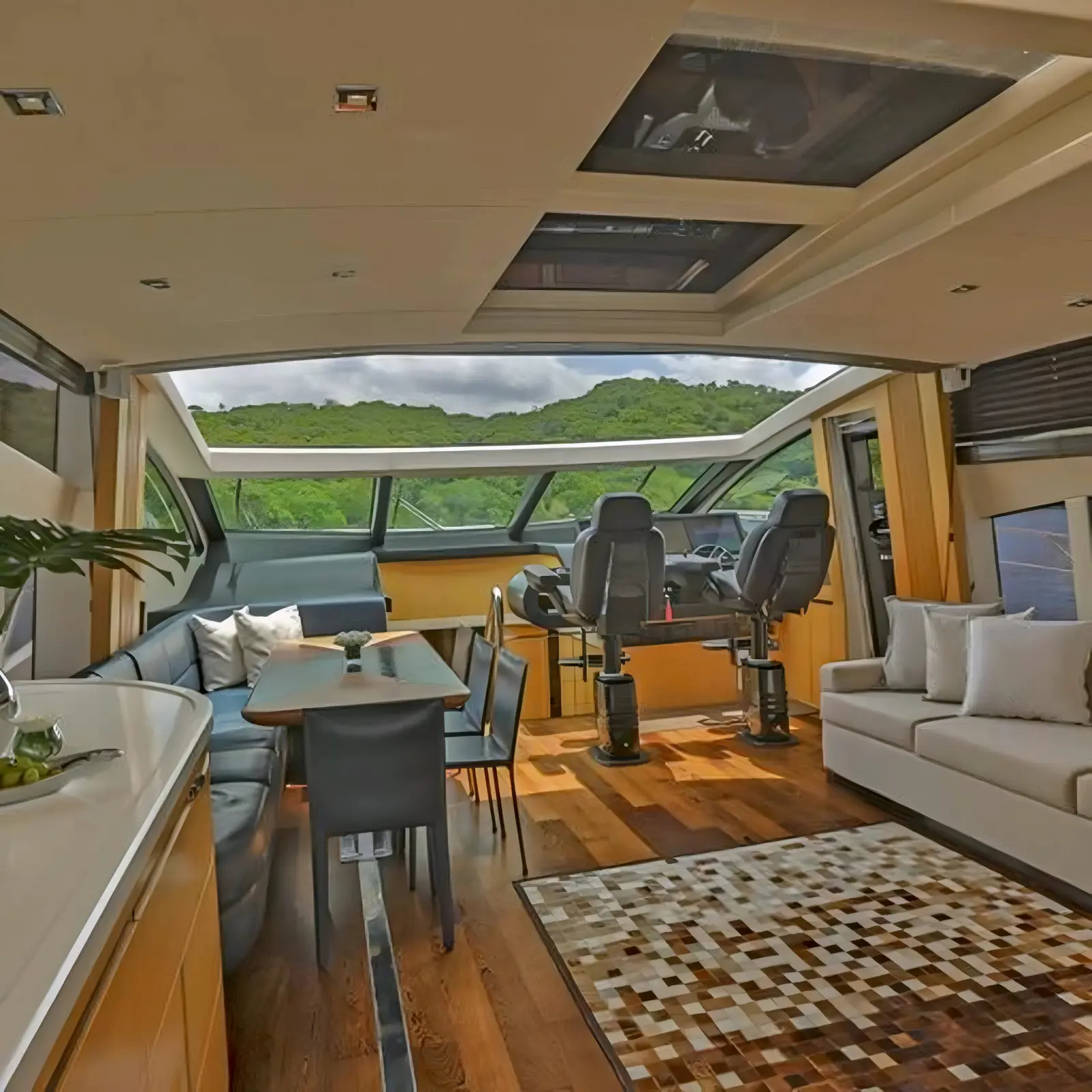 Yacht salon with a wood floor, patchwork rug and dining table leading to the forward helm