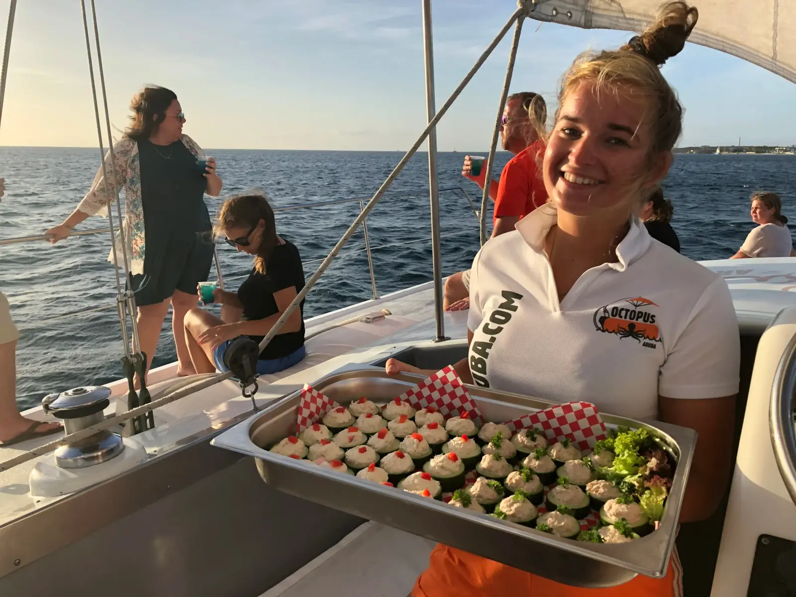Crew member holding a tray of appetizers for guests on a sailing catamaran