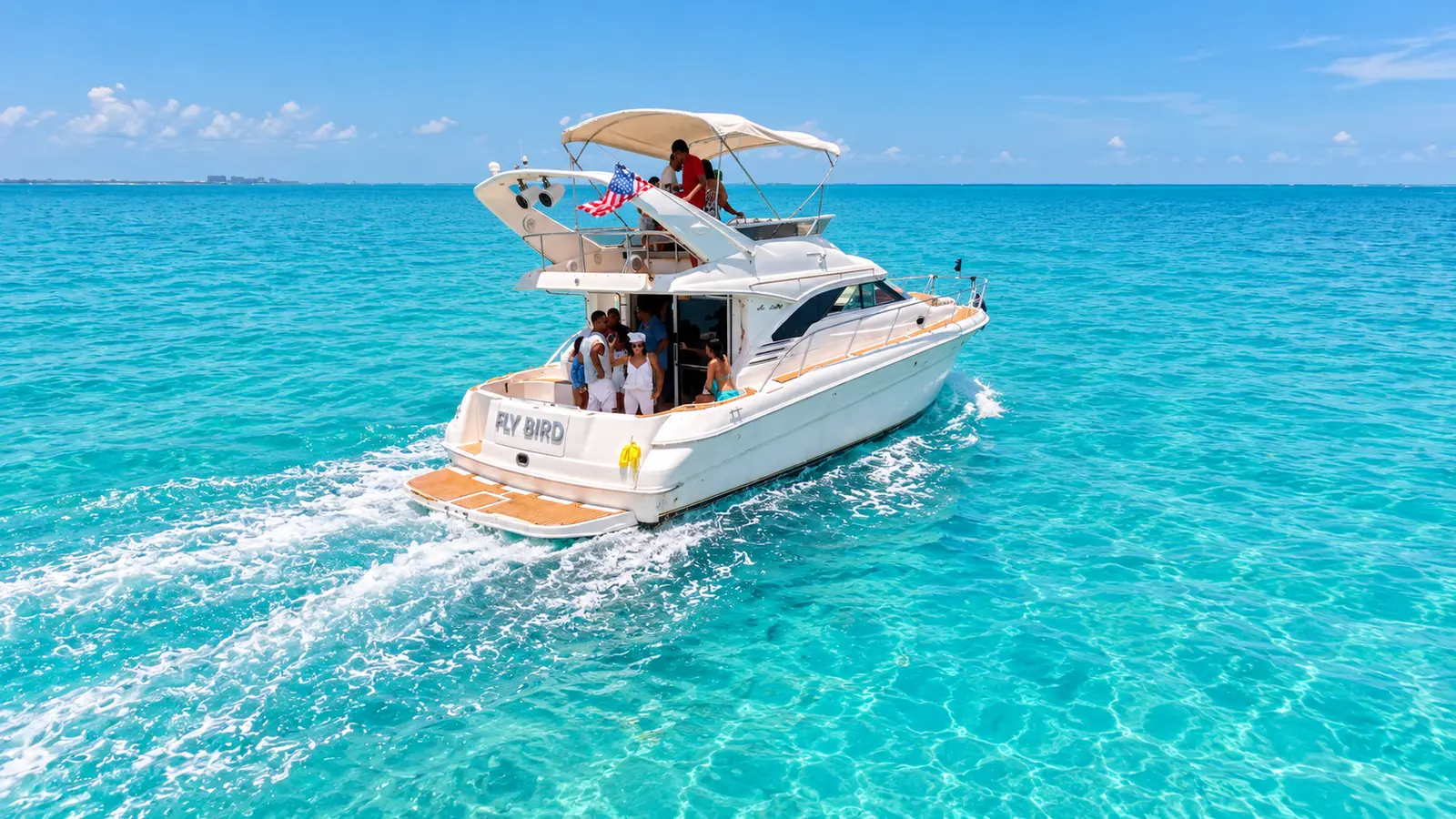 Flybridge motor yacht with guests aboard cruising across bright turquoise water off Cancún