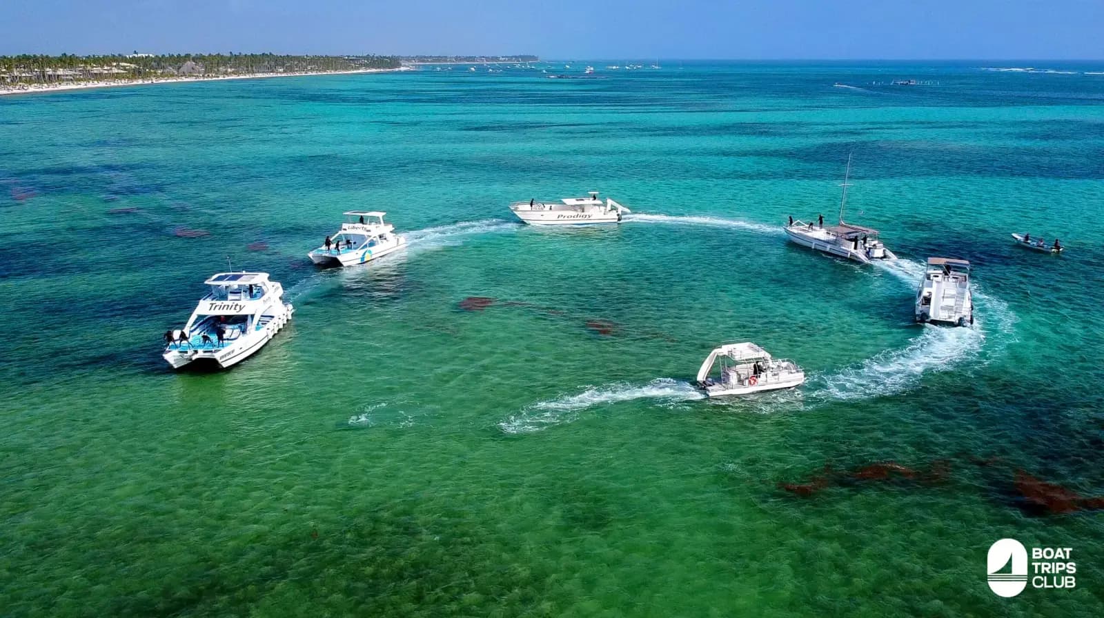 Aerial view of a fleet of catamarans circling in formation over the turquoise reef off Punta Cana