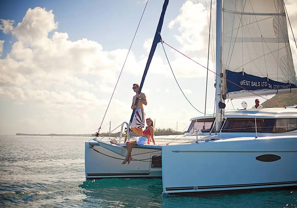 Sailing catamaran anchored in calm shallows with guests perched on its bow off Zanzibar's north coast