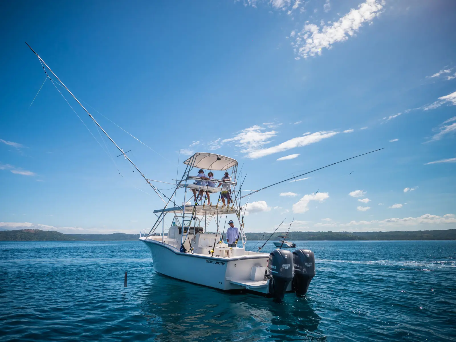 Stern view of a sportfishing boat with twin outboards and outriggers spread on calm water